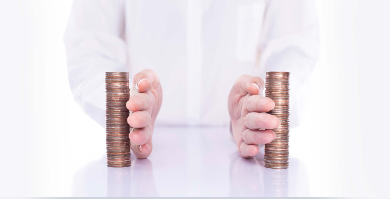 Zwei H&auml;nde teilen M&uuml;nzstapel auf einem gl&auml;nzenden Tisch. Im Hintergrund auf Brusth&ouml;he abgeschnitten, ein Mann in wei&szlig;em Hemd.